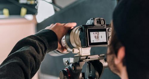 Selective focus of videographer filming woman in photo studio